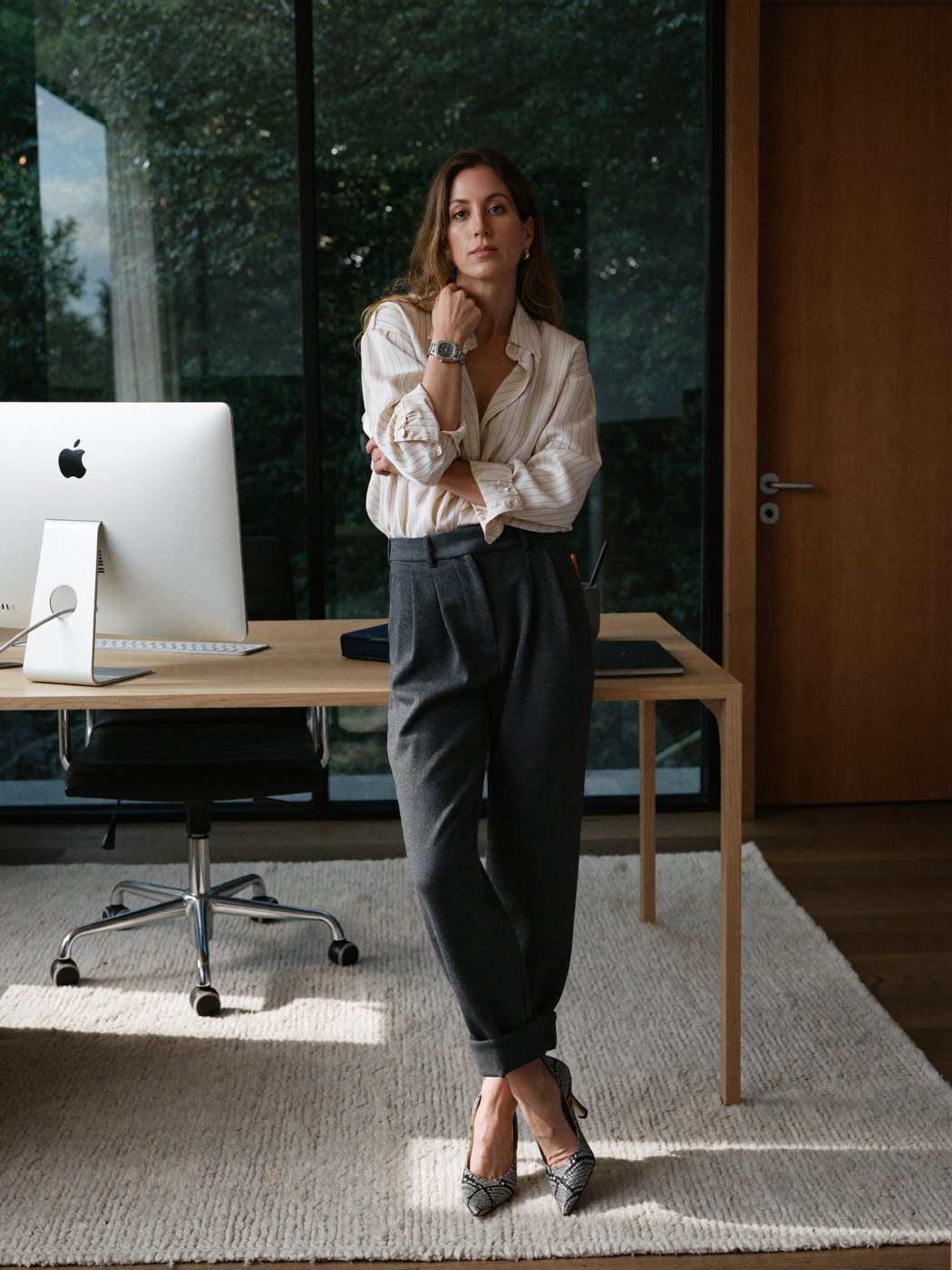 Jeanette Isabella Gunnerød standing at her desk in a striped shirt and grey trousers